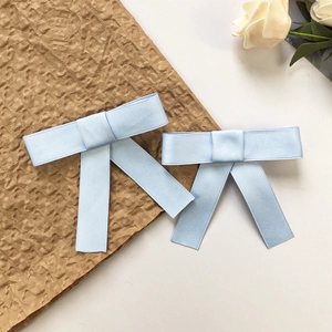 Dettaglio del fermaglio per capelli con fiocco in raso azzurro e texture elegante