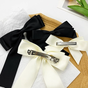 Elegant satin bow hair clips in black and cream white with polished silver metal base