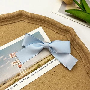 Detailed close-up of light blue satin ribbon bow hair clip on a vintage background
