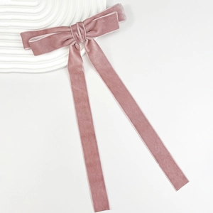 Detail of dusty rose velvet bow hair clip with long ribbons on a wavy white stand