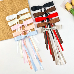Detailed view of ten colorful satin bow hair clips with long streamers and metal alligator clips