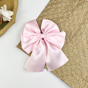 Détail d'un nœud papillon en satin rose avec rubans multicouches et aspect soyeux