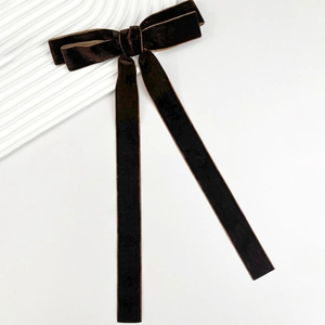 Close-up of chocolate brown velvet bow hair clip with elegant long hanging ribbons