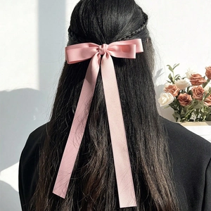 Pink ribbon bow hair clip with long satin streamers shown on hair in elegant style