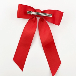 Detail view of the silver metal duckbill clip on the back of a red ribbon bow hair clip