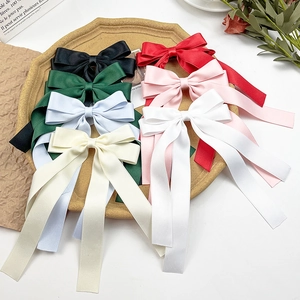 Detail of colorful silk bow hair clips with long ribbons arranged in a rustic wooden tray