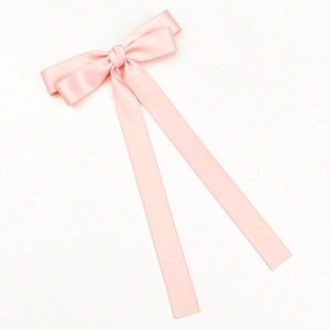 Close-up of pink satin bow hair clip with long ribbons on a white background