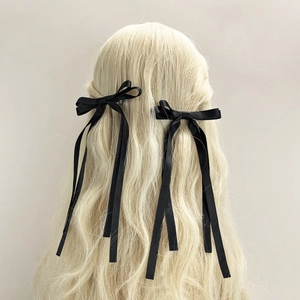 Paire élégante de barrettes à cheveux en ruban de satin noir sur longs cheveux blonds