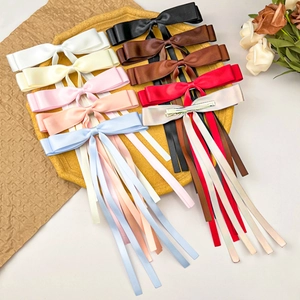 Close-up of assorted colorful satin ribbon bow hair clips on a stone tray display