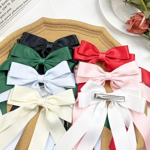 Detailed view of elegant satin bow hair clips in various colors with long ribbons