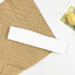 Detail eines weißen gerippten Sport-Stirnbandes auf Papier mit gelber Blumenkarte