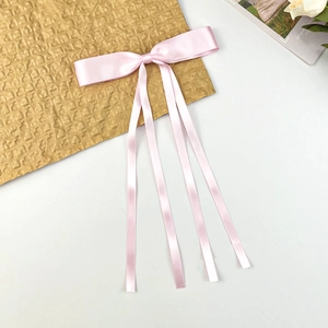 Close-up of soft pink satin ribbon bow with long streamers on a neutral background