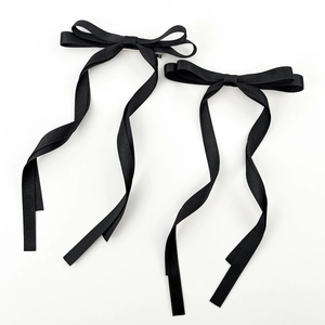 Détail de barrettes à cheveux avec nœud en satin noir, longs rubans et pince en métal