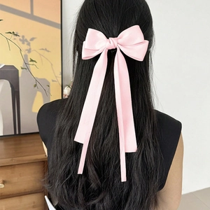 Pink satin double bow hair clip with long ribbons shown on long dark hair