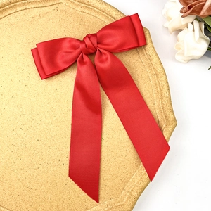 Detail of red grosgrain bow hair clip featuring double layers and long elegant ribbons