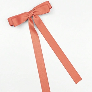 Detailed view of large coral velvet bow hair clip with elegant long flowing ribbons