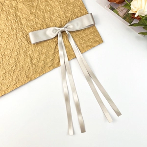 Close-up of champagne satin ribbon bow hair clip with long elegant flowing streamers