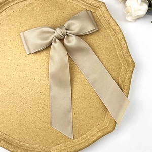 Detail of the champagne beige bow hair clip with ribbed texture and elegant long tassels