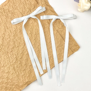 Détails de pinces à cheveux avec nœuds en satin blanc sur papier à motifs cœurs