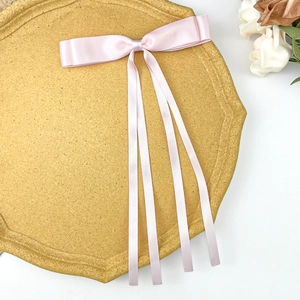 Detailed view of pink satin ribbon hair clip with double bows on a decorative tray