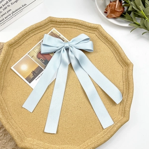 Detail of light blue satin bow hairclip with long ribbons on a decorative tray