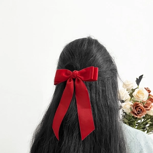 Elegant large red bow hair clip with long ribbons shown on long dark hair