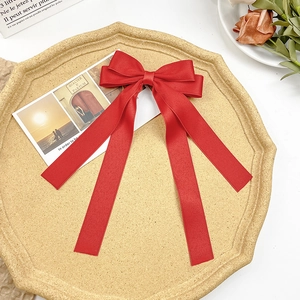 Detail of a bright red satin bow hair clip with long ribbons on a decorative tray