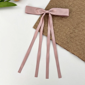 Gros plan du nœud papillon en satin rose avec de longs rubans sur papier texturé