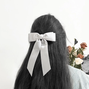 Elegant white bow hair clip with long ribbons on straight black hair for sweet style
