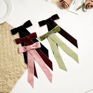 Détail de barrettes à nœuds en velours multicolores avec des clips en métal argenté