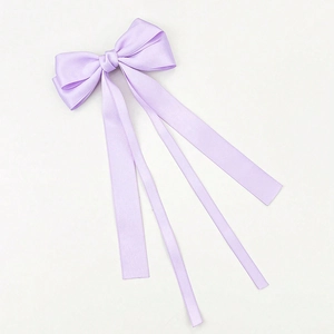 Detail of light purple satin bow hair clip with long ribbons on a plain white surface