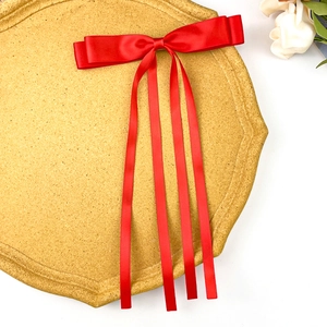 Detail of red satin bow hair clip with long ribbons on yellow display board