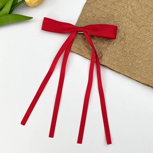 Détail de la pince à cheveux noeud rouge avec longs rubans et texture satinée lisse