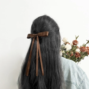 Deep coffee satin bow hair clip with long ribbons shown on model's hairstyle