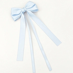 Detail of light blue satin bow hair clip with flowing ribbons and silky texture
