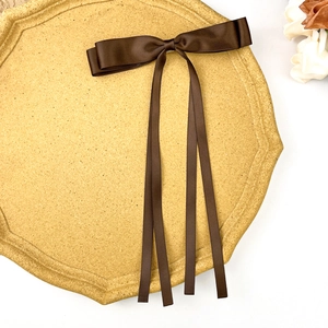 Detail of dark brown satin double-layer bow hair clip with long ribbons on a display tray