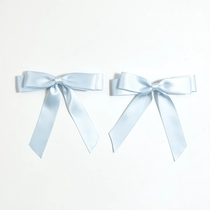 Close-up of light blue satin ribbon hair clips with long elegant streamers in a set of two
