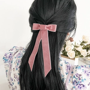 Barrette à cheveux nœud en velours rose avec longs rubans portée par un mannequin