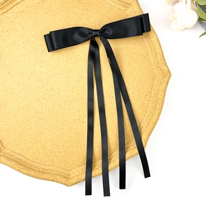 Elegant double-layered black satin ribbon hair bow with long streamers on gold display