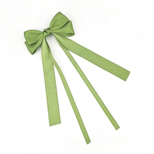 Close-up of olive green satin bow hair clip with three long flowing silk ribbons