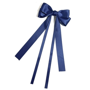 Detailed view of a navy blue satin bow hair clip with elegant long ribbons on white background