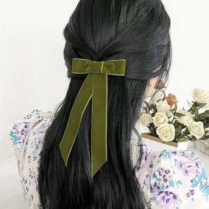 Détail de la pince à cheveux en velours vert foncé avec de longs rubans sur cheveux noirs