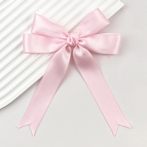 Gros plan sur la barrette à nœud en satin rose avec de longs rubans élégants