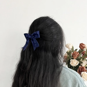 Detail van een donkerblauwe fluwelen strik haarclip gedragen in een half opgestoken kapsel