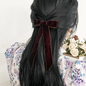 Détail macro du nœud en velours rouge vin avec de longs rubans sur cheveux noirs