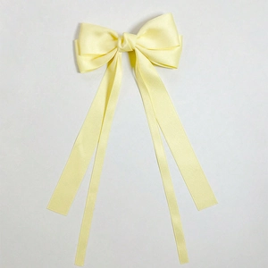 Detailed view of light yellow satin bow hair clip with long ribbons and smooth texture