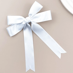 Détail d'un élégant nœud de satin blanc avec de longs rubans sur un fond neutre