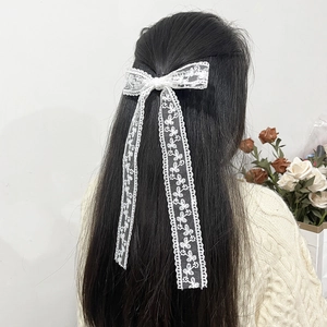 Elegant white lace floral bow hair clip with long ribbons on black hair