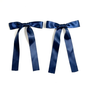 Detail of two dark blue satin bow hair clips with long elegant ribbon streamers