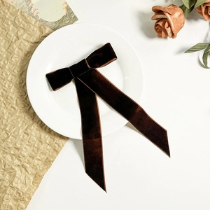Détail d'un nœud en velours marron foncé avec de longs rubans sur fond décoratif